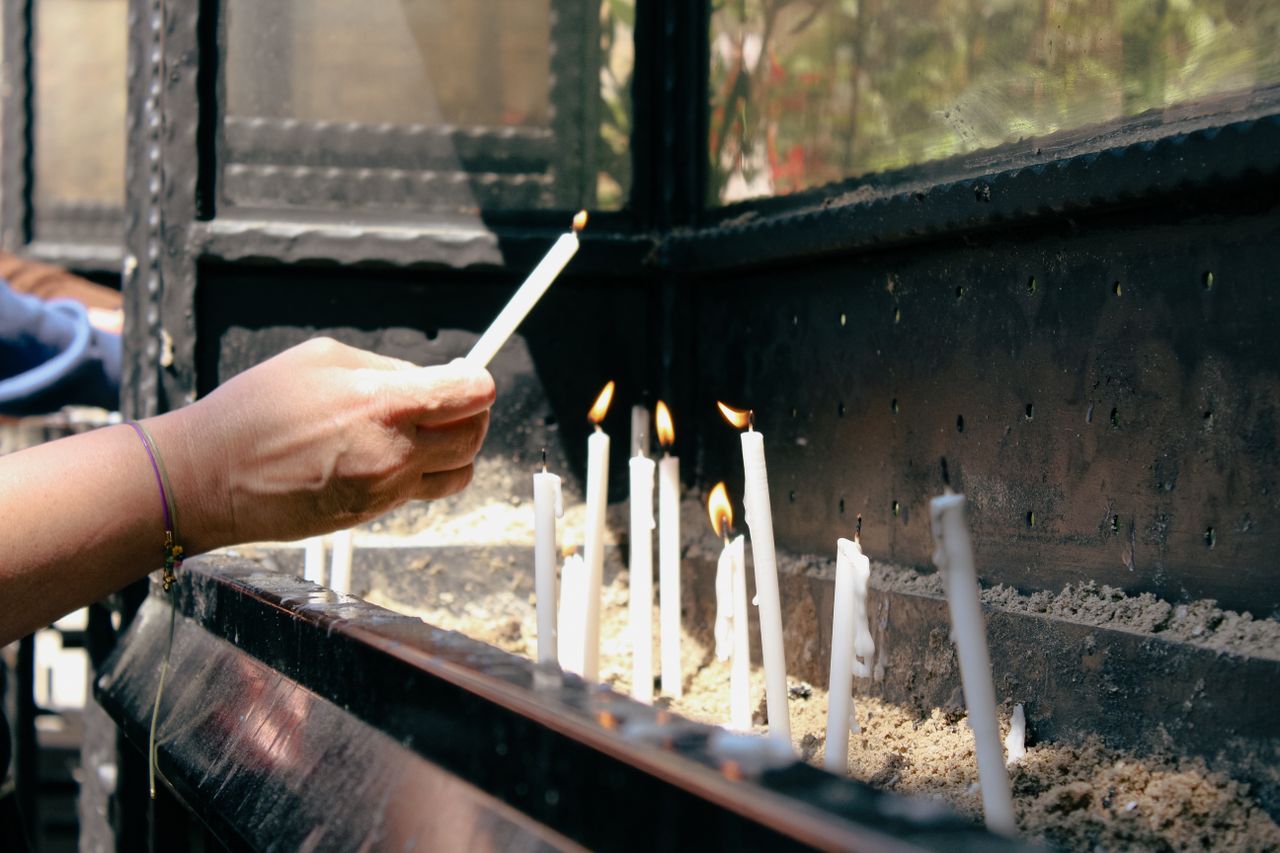 A hand lighting candles in a sacred setting, symbolizing peace and prayer.