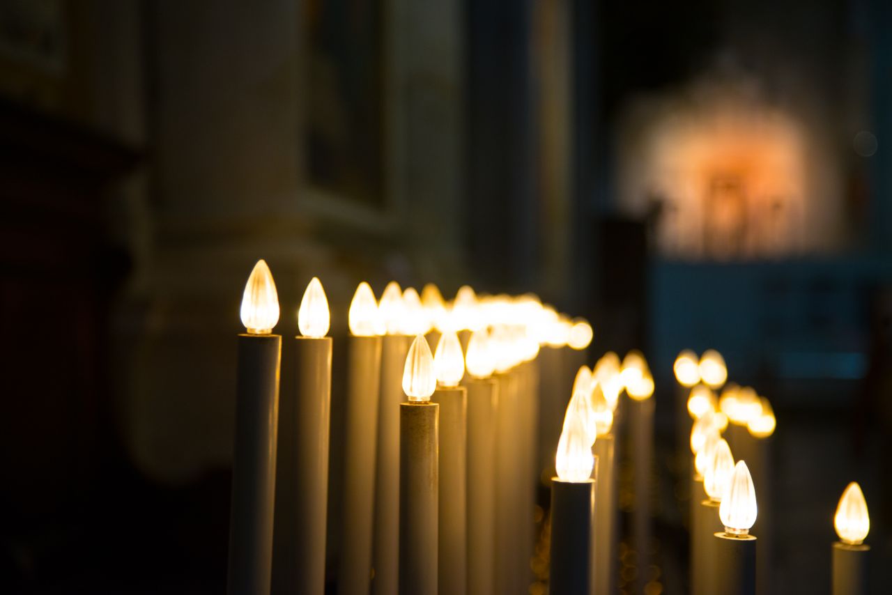 Candles casting a warm glow in a dimly lit indoor environment, creating a serene atmosphere.