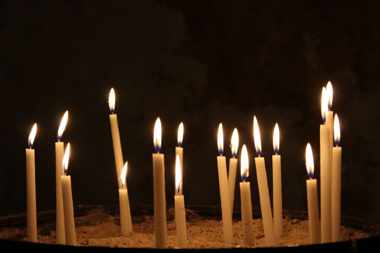 A serene arrangement of lit candles glowing softly in a dimly lit environment.