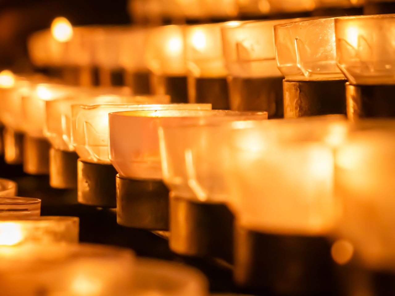 Rows of glowing candles create a warm, spiritual atmosphere in a peaceful sacred space.
